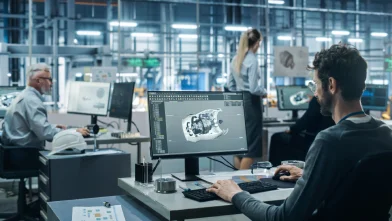 Imagen de un hombre en su estación de trabajo, trabajando en un modelo 3d de una pieza de un vehículo.
