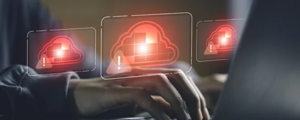 Engineer typing on a laptop with red cloud warning icons representing denied cloud software license checkouts