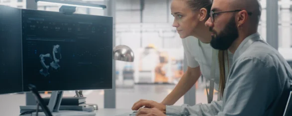 Two engineers reviewing a license and asset monitoring dashboard on a workstation in an engineering facility.